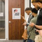 Voters in line to vote while looking at phones