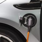 Electric vehicle plugged in and charging, gray