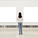 Woman standing in front of blank canvases in exhibit space