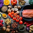 An overhead view of a spread of raw foods, including red cabbage, avocado, mushrooms and salmon. 