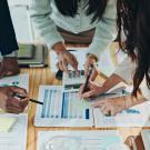 Business team collaborating over printed charts and tablets on a wooden table
