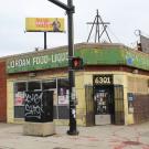 Corner store with a green awning, brick exterior, and a street sign nearby.