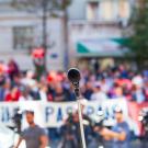 Microphone on stand at outdoor rally, blurred crowd and banners in background