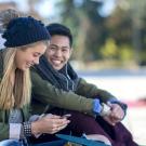 Young couple wearing jackets talking to each other outdoors