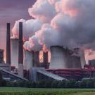 Power station chimneys emit billowy clouds of smoke and steam aainsta dramatic red sunset light. 