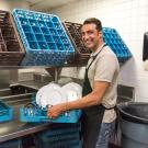 Man working among dishes in back of restaurant