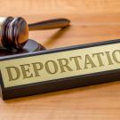 Judicial gavel on desk next to word "deportation" on a name plate