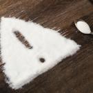 White powder shaped into a warning triangle with an exclamation mark and a spoon on wood