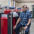 Seated male scientist next to helium recovery equipment 