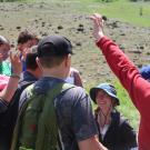 students raise their hands around UC Davis research fellow, Leta Landucci