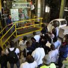 Joshua Morejohn stands in front of a steam system at UC Davis talking with group of visitors.