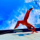 Woman doing dance routine with blue sky in background