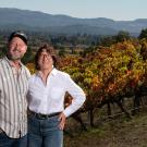 Man and woman stand at the top of a hill on a vineyard