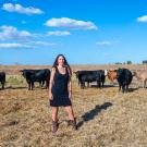 Woman stands in field with cows