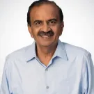 Smiling middle-aged man with mustache wearing light blue shirt, neutral background