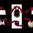 Red-gloved hands hold assorted wigs and masks on white panels against black background