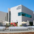 Modern white building with outdoor tables and umbrellas under clear blue sky
