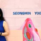 Woman stands in front of a pink wall