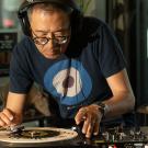 Man wearing headphones and blue target t-shirt adjusts vinyl on turntable in sunlit store