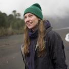 Toby Kiers stands at water's edge in coat and hat