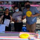 Three people hand out flyers at an outreach event.