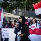 Woman at protest. Colorful flags surround her.