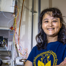 Female scientist in blue tee shirt in lab setting. 