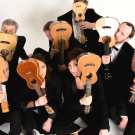 Band of people in black suits holding ukuleles