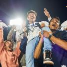 Jubilant Aggie football fans lift one of their own into the air.