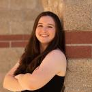 Amanda Portier leans against an exterior wall of the Alumni Center