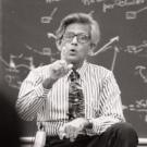 Amiya Mukherjee, sitting on desk, teaching