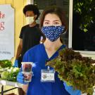 Woman in mask holds snacks and produce.