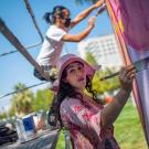 Woman closeup and man painting colorful mural on large wall.