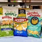 Assorted colorful chip and snack bags that claim they are made with avocado oil are lined on a table inside a lab. These chips were among the 54 avocado-labeled products tested in the Wang lab at UC Davis. (Selina Wang / UC Davis)