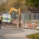 A cyclist rides in front of a construction site.