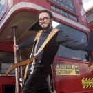 Smiling man on the back of red double-decker bus