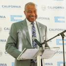 Chancellor in suit and tie at lectern, smiling