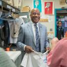 Chancellor May, in suyit and tie, smiles while holding screen-printed T-shirt and being interviewed live for morning TV show