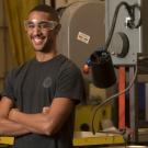 A male student poses with a machine press