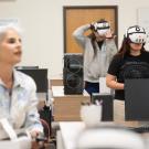 Classroom scene with two people wearing VR headsets at desks, instructor in foreground.