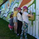 Young girls paint mural on the side of a building.