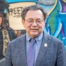 Man in dark suit in front of mural 