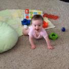 Smiling infant on carpet with toys 