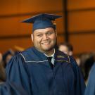 A student smiles among friends in his cap and gown at UC Davis. 