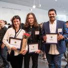 Three people holding award plaques with crowd in background in the Mondavi lobby of Manetti Shrem Museum, UC Davis