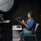 A student smiles in a podcast studio at UC Davis. 