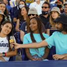 Student speaks into microphone while sitting in stadium crowd.