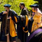 Law graduates greet each other by bumping elbows.