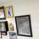 Gallery wall with assorted framed artworks and small sculptures on a shelf.