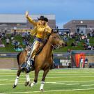 Student rides horse onto football field.